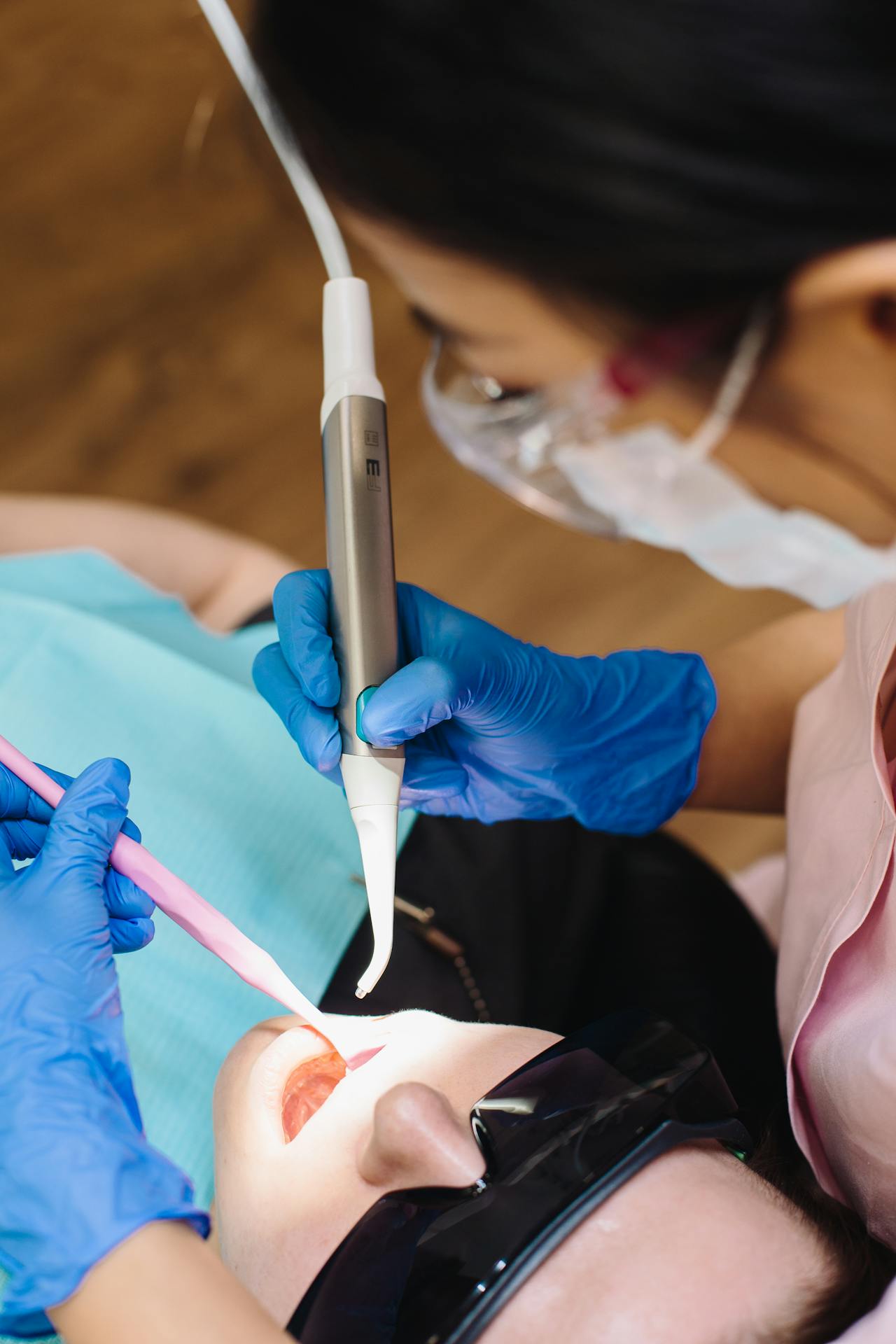 dentist with black hair treating patient in dental chair