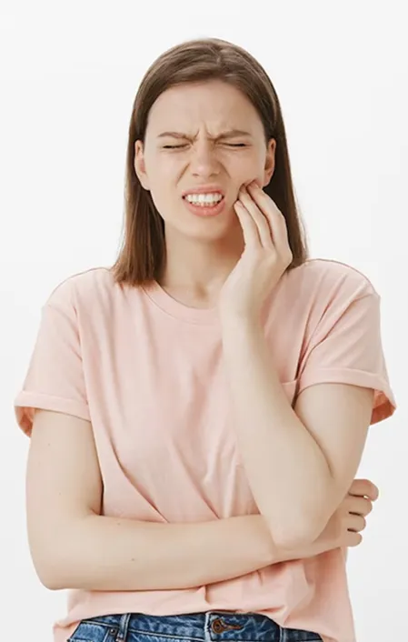 woman wearing pink in pain holding side of cheek