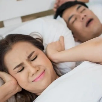 Woman Holding Ears With Husband Snoring Next To Her Thumbnail