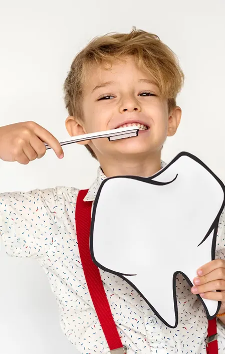young kid brushing teeth and holding tooth sign