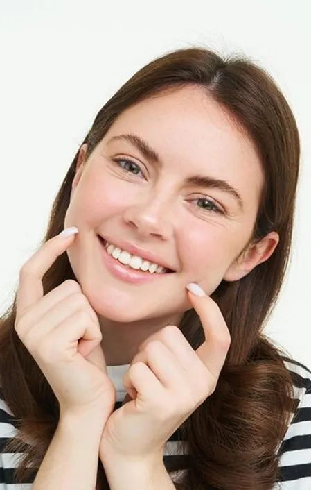 woman smiling pointing to her white teeth