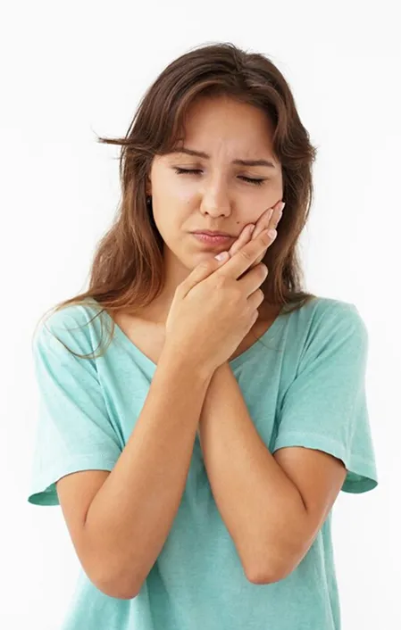 woman with blue shirt holding side of face with toothache