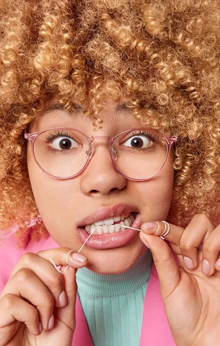 woman with brown afro hair flossing gums