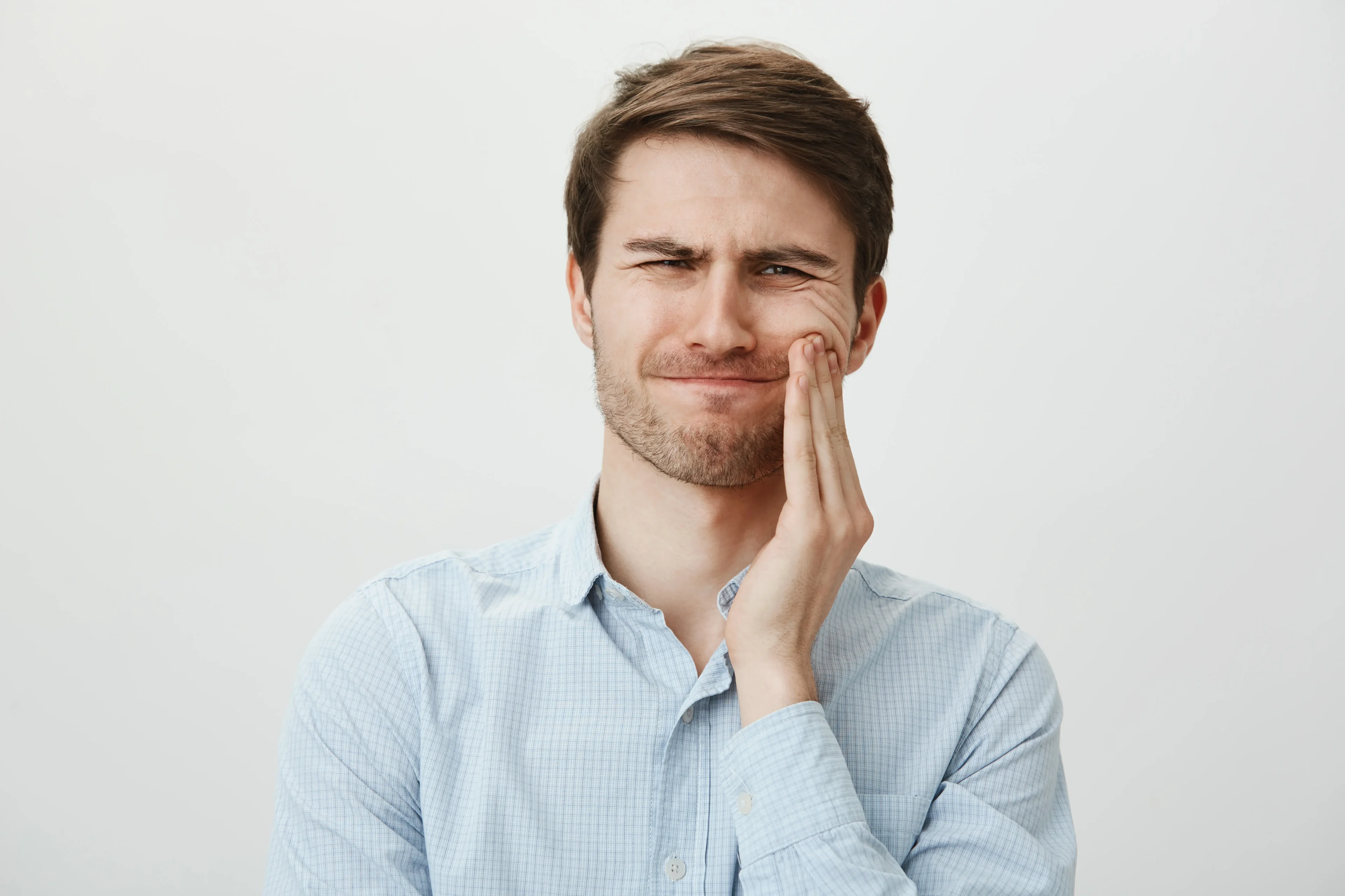 Man Touching Cheek Grimacing From Pain From Toothache